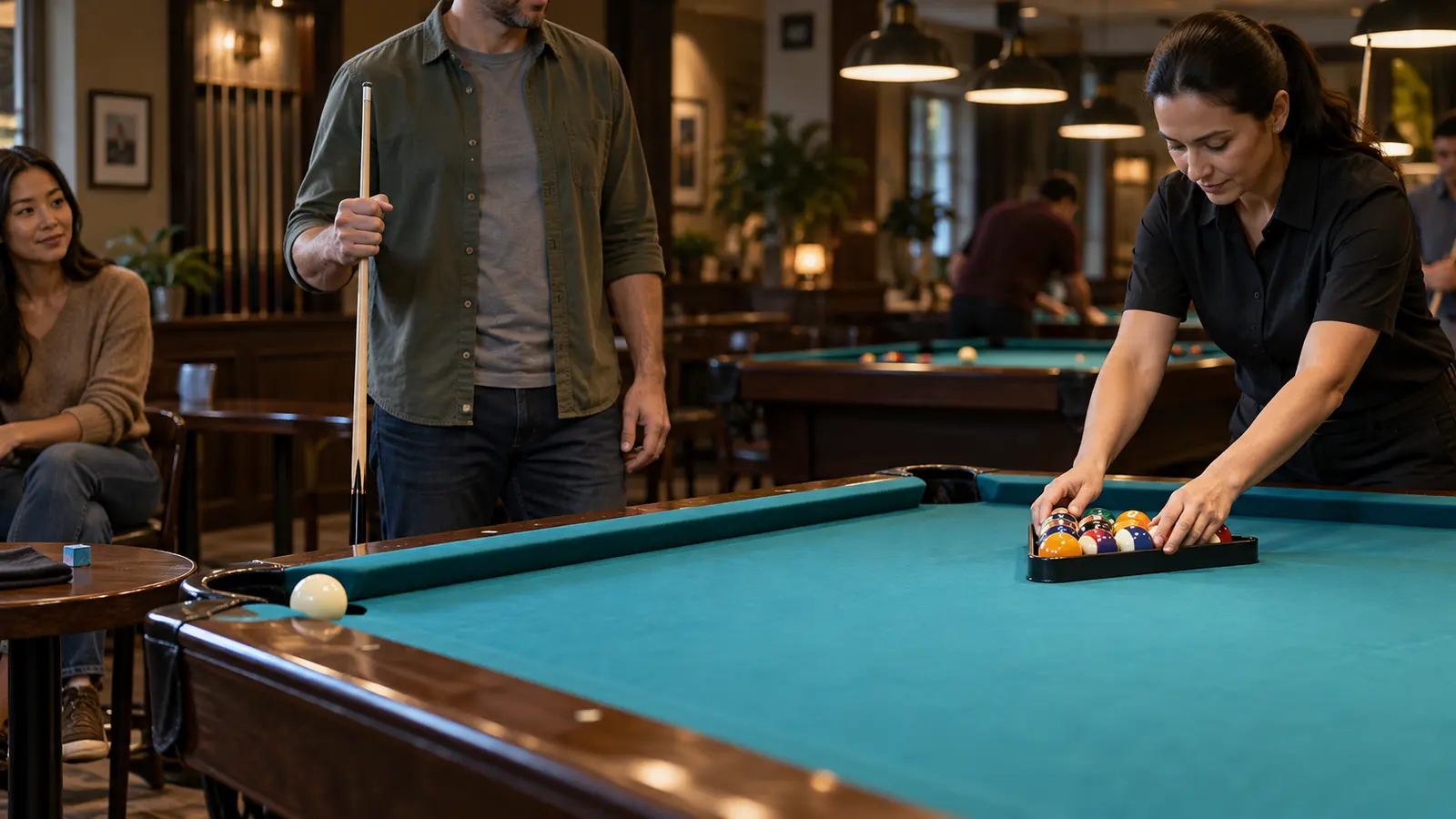 Pool players checking a clear table area while an attendant sets a rack and cues are held safely away from the cloth