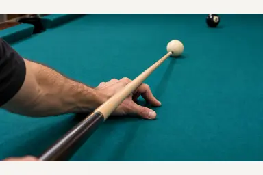 Editorial close-up of a real bridge hand and straight cue without ghost shafts or an inferred grip-wrist measurement